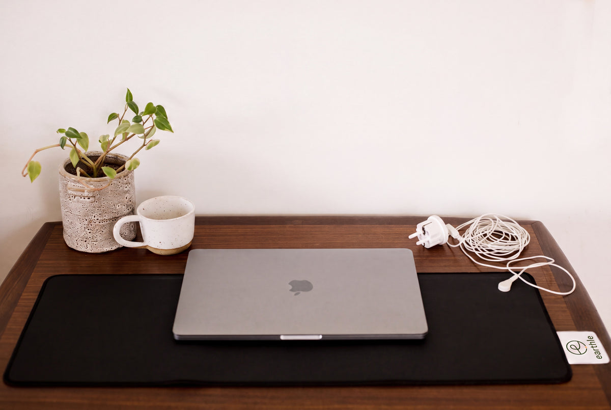 Earthle Erdungs-Schreibtischmatte auf einem Schreibtisch mit Laptop, Pflanze und Becher, Kabel zur Steckdose